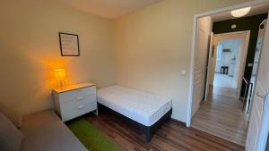 a small bedroom with a bed and a lamp on a dresser at Le Pegan - Appartement 2 chambres proche du centre de Ferney et de Palexpo in Ferney-Voltaire