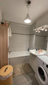 a bathroom with a tub and a sink and a washing machine at Le Pegan - Appartement 2 chambres proche du centre de Ferney et de Palexpo in Ferney-Voltaire