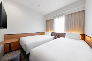 a hotel room with two beds and a television at Sotetsu Grand Fresa Osaka-Namba in Osaka