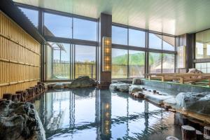 a large pool of water in a building with windows at 六日町温泉 龍氣 in Minami Uonuma