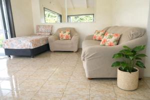 a living room with a couch and a chair at Hidden Haven - Group Retreat-Sleeps 7 aircon & free Wifi in Rarotonga