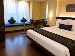 a hotel room with a large bed and a window at Marasa Sarovar Portico -Rajkot in Rajkot +85 photos