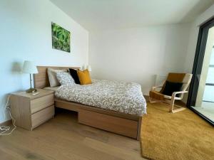 a bedroom with a bed and a table and a chair at Apparté - Appartement proche Genève et Palexpo in Ferney-Voltaire