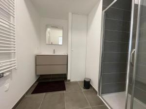 a white bathroom with a sink and a shower at Apparté - Appartement proche Genève et Palexpo in Ferney-Voltaire