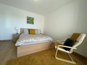 a bedroom with a bed and a chair at Apparté - Appartement proche Genève et Palexpo in Ferney-Voltaire +9 photos