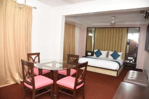 a hotel room with a table and a bed at Belair Suites in Pune +6 photos