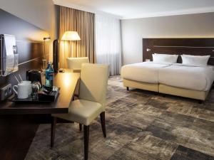 a hotel room with a bed and a desk with a desk at Mercure Hotel Hagen in Hagen +42 photos