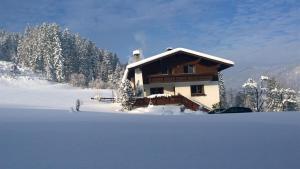 a house with a snow covered roof in the snow at Ferienwohnungen Dagn in Kössen