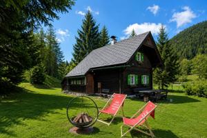 a log cabin with two red chairs and a fire hydrant at Almhütte am Steirischen Seeberg in Turnau