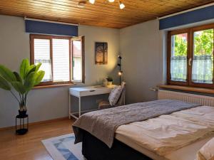 a bedroom with a bed and a desk and windows at Ferienhaus zur Altmühl - Ferienwohnungen & Gartenhäuser in Ornbau