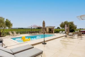 a swimming pool with chairs and umbrellas at La Maison Blanche in Saint-Sulpice-de-Faleyrens