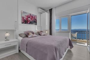 a white bedroom with a bed and a balcony at Villa King Apartments in Brela +24 photos