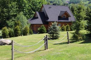 a log cabin with a chain fence in front of a house at Mosorny Park Zawoja Całoroczne domki w górach in Zawoja
