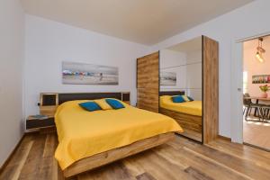 a bedroom with two beds with yellow sheets and blue pillows at Deja near centar and Čikat bay with private parking in Mali Lošinj