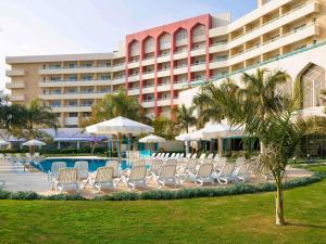a group of chairs and umbrellas in front of a hotel at Mercure Ismailia Forsan Island in Ismailia