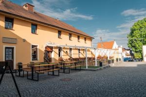 a building with wooden tables in front of it at Hotel Purkmistr Beer & Spa Resort in Pilsen