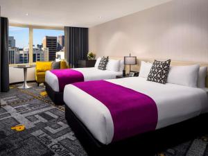 two beds in a hotel room with a view at Pullman Melbourne City Centre in Melbourne