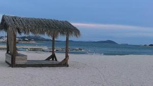 a straw hut on a beach with the ocean at Apartments Prisnac in Pakoštane