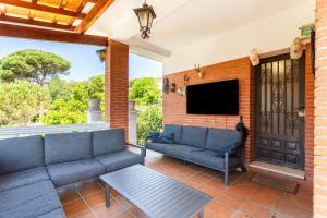 a patio with a couch and a tv on a brick wall at Villa Toro in Maçanet de la Selva
