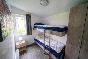 a small room with two bunk beds and a window at EuroParcs Markermeer in Bovenkarspel