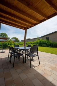 a patio with a table and chairs under a wooden roof at EuroParcs Markermeer in Bovenkarspel
