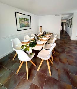a long dining room with a long table and white chairs at Gandia Confort Treviso in Gandía
