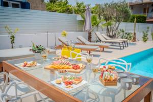 a table with food and wine glasses next to a pool at Seaside Hideaway Villa in Perivolia