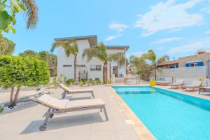 a swimming pool with lounge chairs next to a house at Seaside Hideaway Villa in Perivolia