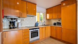 a kitchen with wooden cabinets and a stove top oven at Clube Alvor Ria - Prime Residence in Alvor