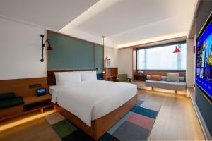 a hotel room with a bed and a tv at Manxin Hotel Shenzhen Longgang in Longgang