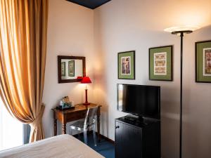 a hotel room with a bed and a desk with a television at Phi Hotel Palio in Asti