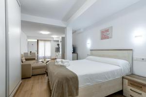 a bedroom with a large white bed and a couch at Oasis Cordobés in Córdoba