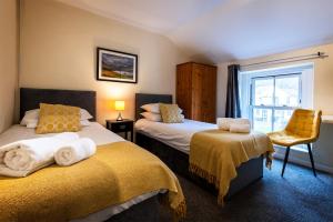 a bedroom with two beds and a chair and a window at Strands Hotel/Screes Inn & Micro Brewery in Nether Wasdale