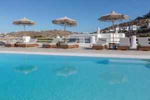 a swimming pool with chairs and umbrellas on a beach at Evagelia's Place in Agios Ioannis Mykonos