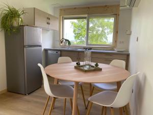 a small kitchen with a wooden table and white chairs at Le pré du bonheur in Saint-Georges-sur-Baulche