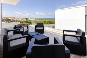 a row of black chairs on a balcony with the ocean at Villa Atlantica One Sea View - Pool - Sunset in Lourinhã