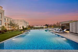 a pool with lounge chairs next to a building at Courtyard by Marriott Gorakhpur in Gorakhpur
