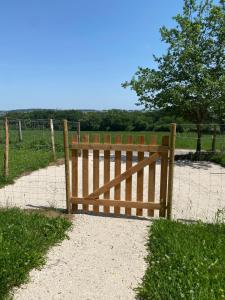 a wooden gate in a field with a fence at Le pré du bonheur in Saint-Georges-sur-Baulche +7 photos