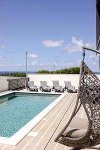a swimming pool with chaise lounge chairs next to the ocean at Villa Atlantica One Sea View - Pool - Sunset in Lourinhã