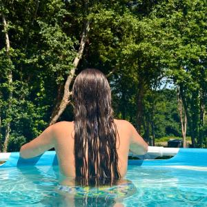 a woman is sitting in a swimming pool at Ker Rev Home Gîte indépendant de charme en longère bretonne in Quimper