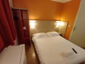 a bedroom with a white bed with two pillows at Hôtel Toulouse Labège in Labège