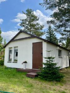 a small white house with a brown door at Rest-Inn Timber-Lake in Kłodno