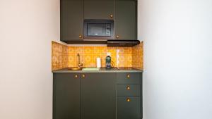 a kitchen with green cabinets and a microwave at Pop Hôtel in Dijon