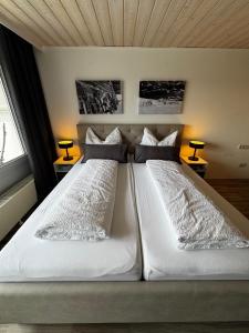 a bedroom with two beds with white sheets and pillows at Allgäuauszeit mit Bergblick - Sauna - Balkon in Scheidegg +19 photos