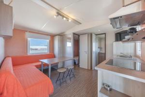 a living room with an orange couch and a kitchen at Bungalow Tranquilo Cerca de Roche in Conil de la Frontera