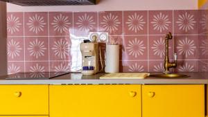 a kitchen counter with yellow cabinets and pink tiles at Pop Hôtel in Dijon +149 photos
