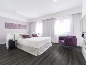 a white bedroom with a large bed and a purple chair at Mercure São Paulo Ibirapuera Privilege in São Paulo