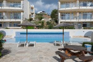 a swimming pool with chairs and umbrellas in front of a building at Apartment Kreta in Strandnähe in Pilalímata