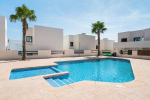 a swimming pool in front of a house with palm trees at Bungalow Fausto Sunrise in Orihuela Costa +12 photos