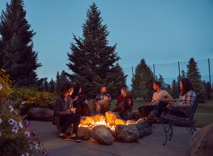 Un groupe de personnes assises autour d'un feu dans un parc dans l'établissement Grouse Mountain Lodge, à Whitefish